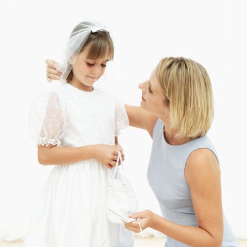 Young woman talking to a girl (11-13) wearing her first holy communion dress
