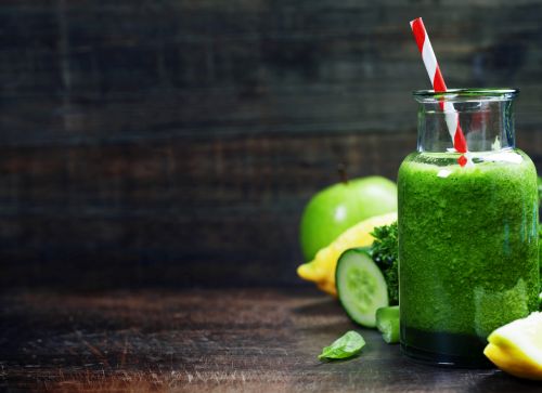 Fresh organic green smoothie with spinach, cucumber, parsley, celery and lemon on wooden background