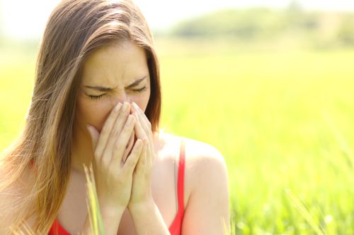 Woman with allergy coughing in a green color field in summer